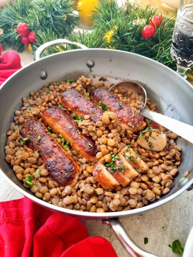 lentils and sausage in a pan with christmas decor in the background