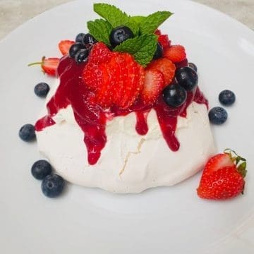 mini pavlova with berries and cream on a white plate