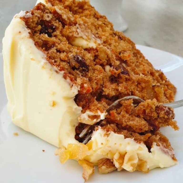 slice of carrot cake with icing with a fork slicing through it.