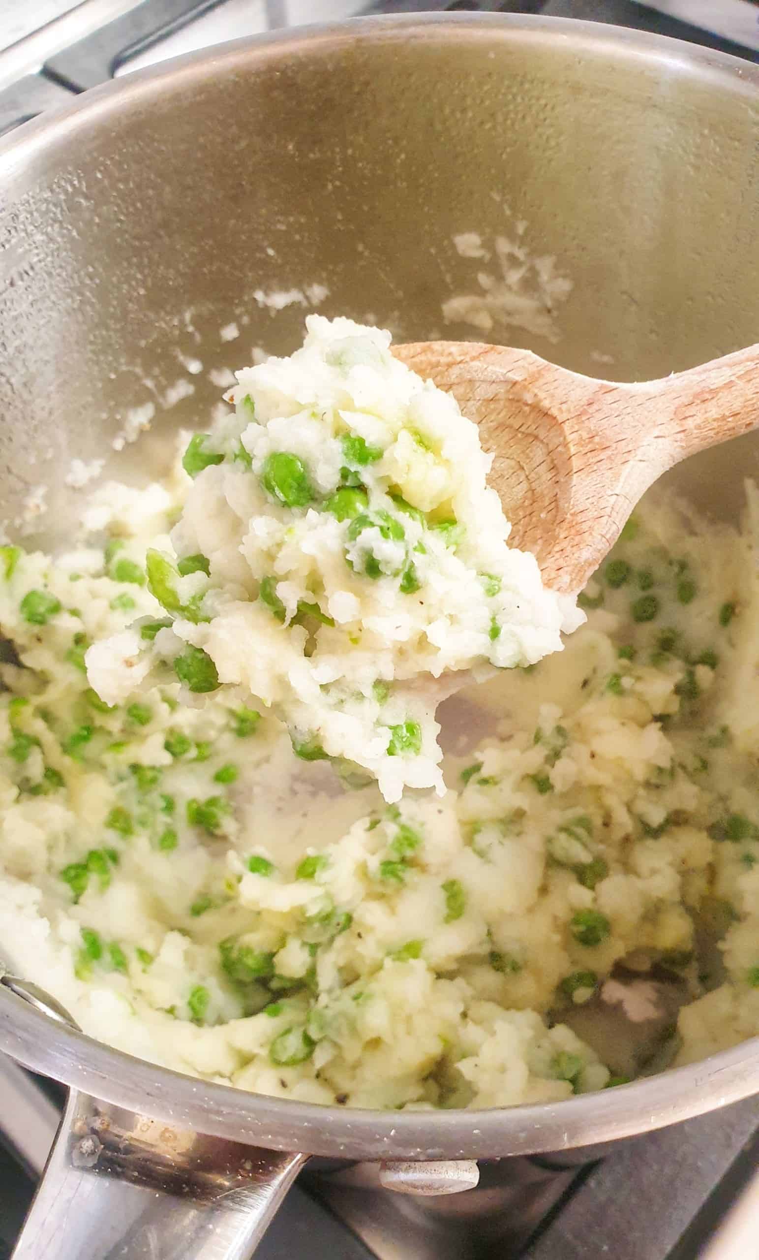 mashed potato with peas on a wooden spoon lifted up for carving