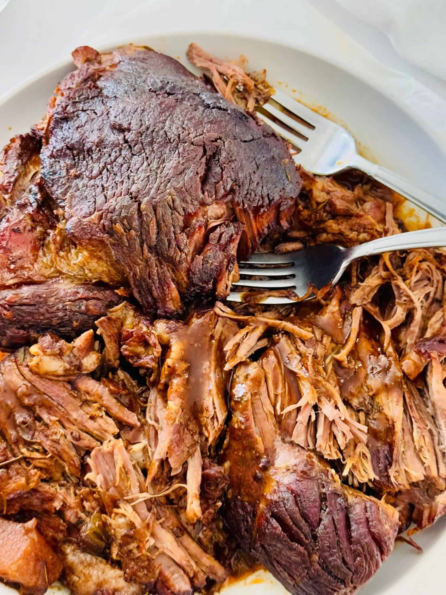 pot roast boneless beef chuck on a white plate and two forks