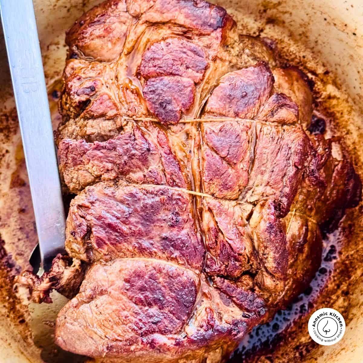 seared beef chuck in dutch oven with tongs