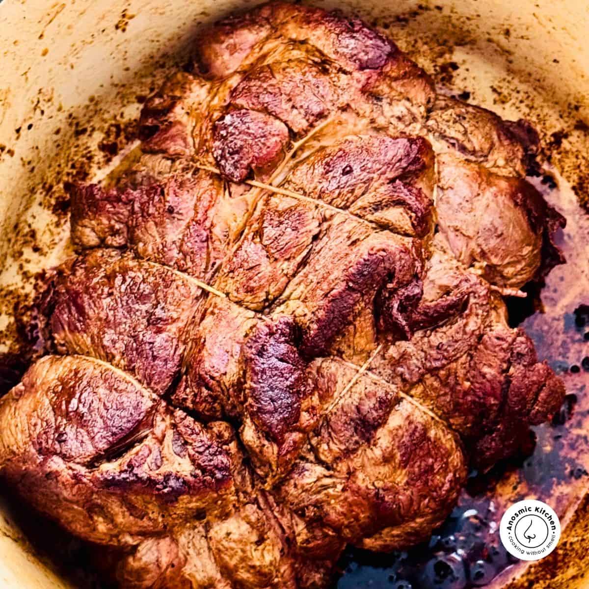 well seared large beef chuck roast inside a ductch oven