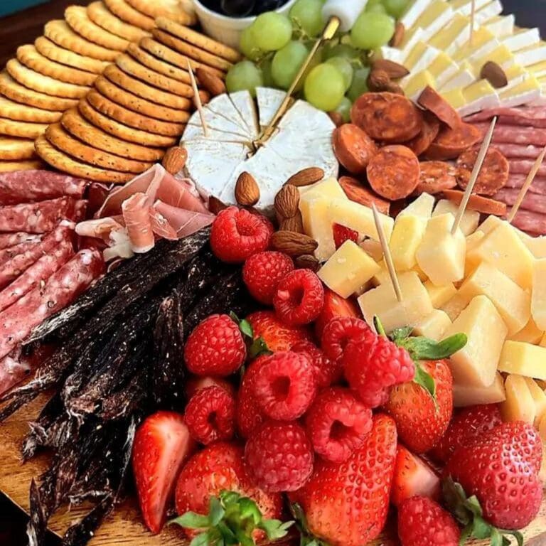 Italian inspired charcuterie board with crackers, olives, cheese, cured meats, biltong, berries and grapes.