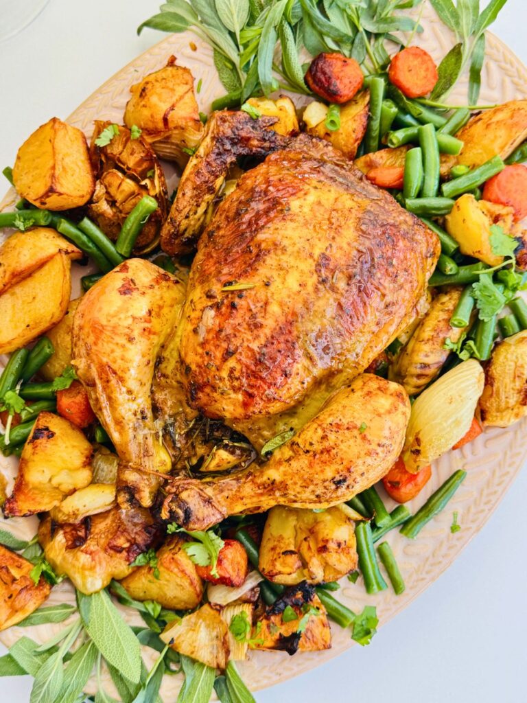 whole chicken roast with veggies and fresh herbs decorated around the chicken