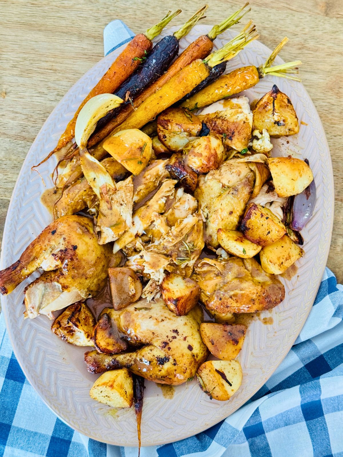 roast chicken pieces on a platter with gravy for serving and roasted veg on the side
