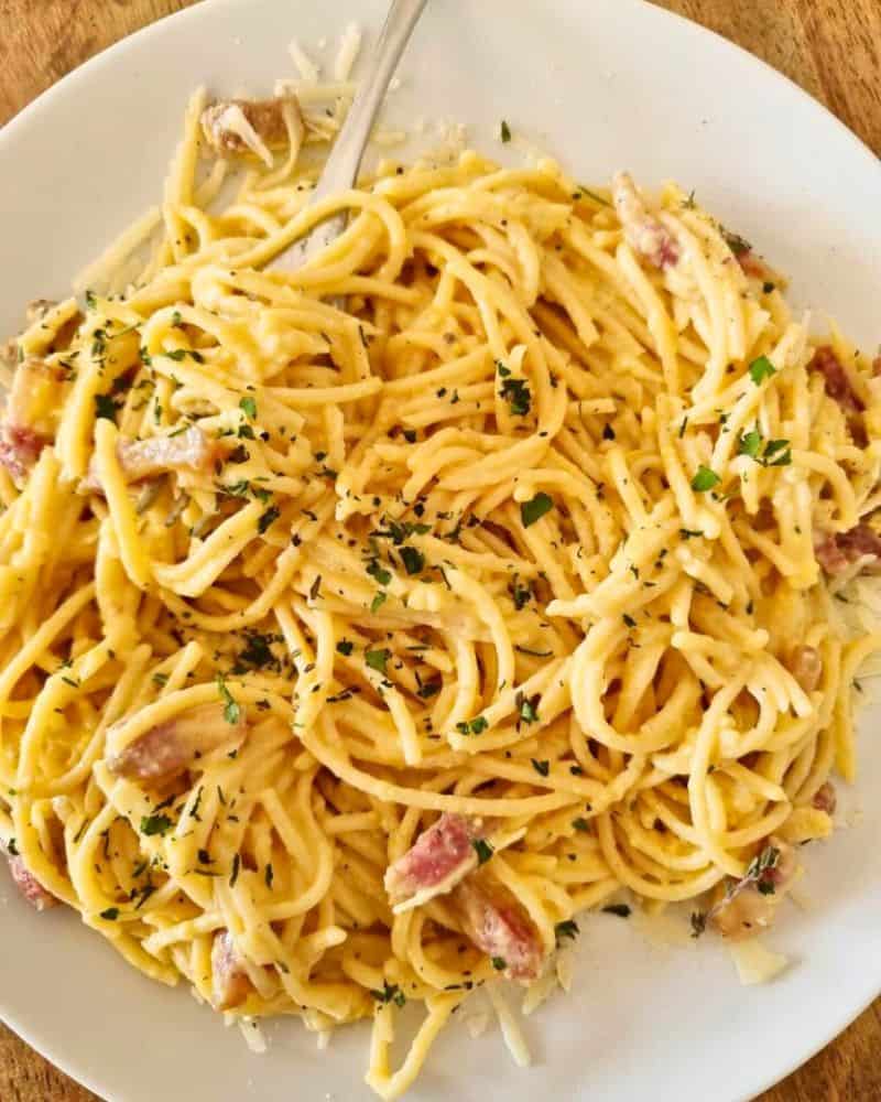 spaghetti carbonara with guanciale and eggs on a plate served with black pepper and parmesan cheese