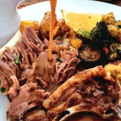 lamb roast bone-in shredded with gravy pouring over