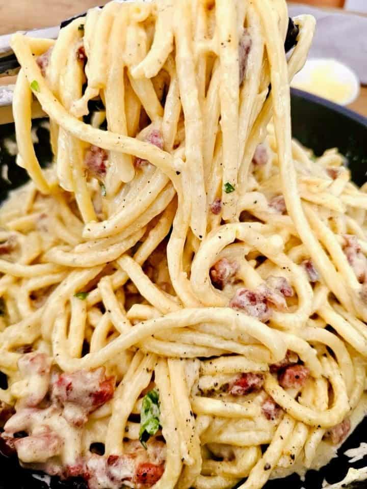 Creamy bacon pasta twirled around a fork with rich, velvety sauce and spaghetti piled beneath.