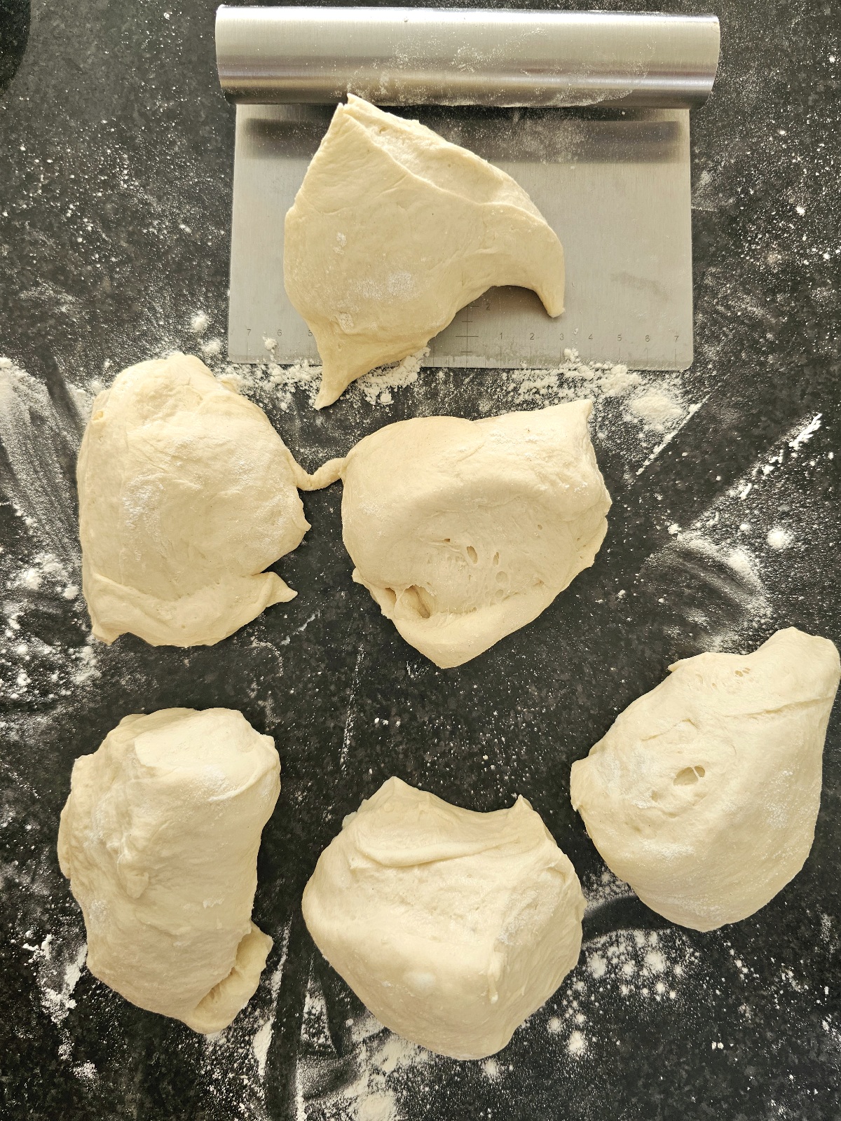 homemade dough on a work surface cut into equal parts for naan bread recipe