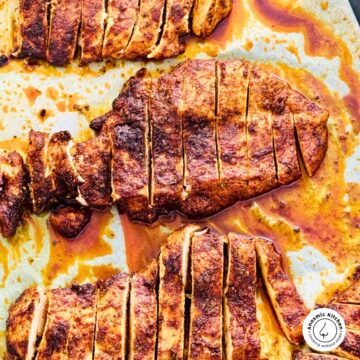 Juicy oven baked chicken breasts sliced on parchment paper