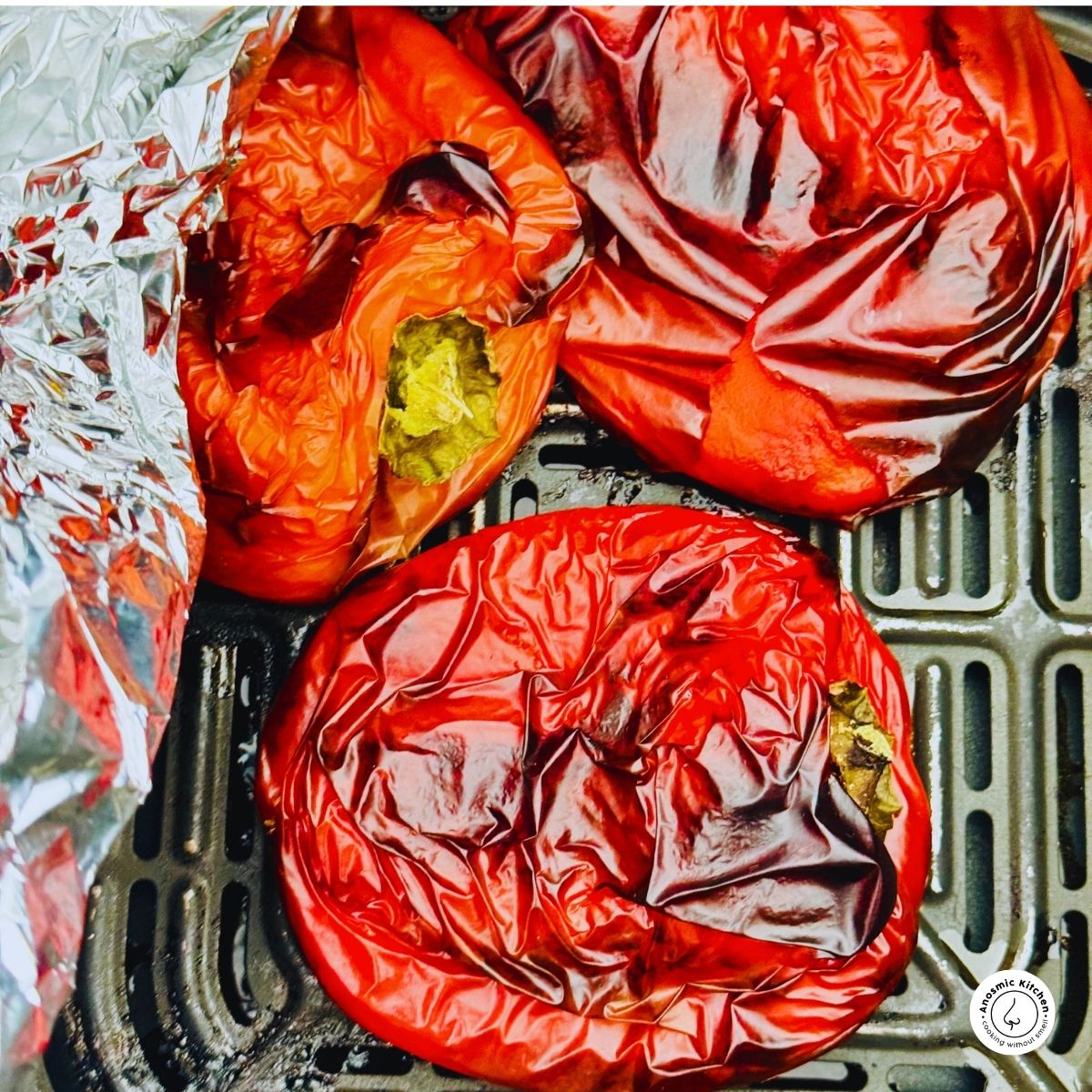 charred red bell peppers in air fryer basket with foil