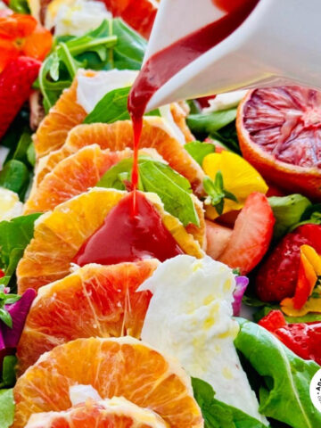 orange salad slices with a blood orange dressing pouring out the jug