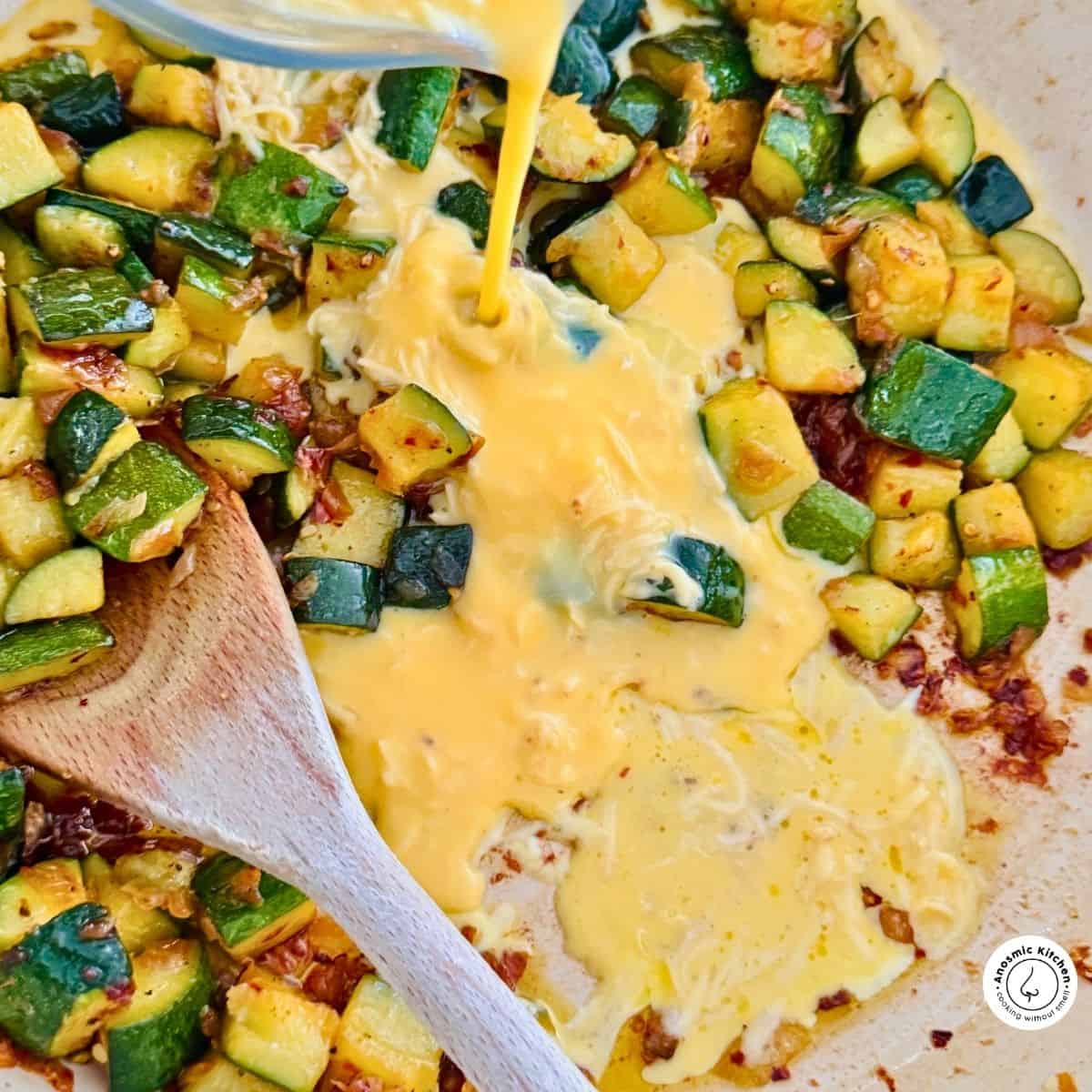 beaten eggs pouring into zucchini to cook