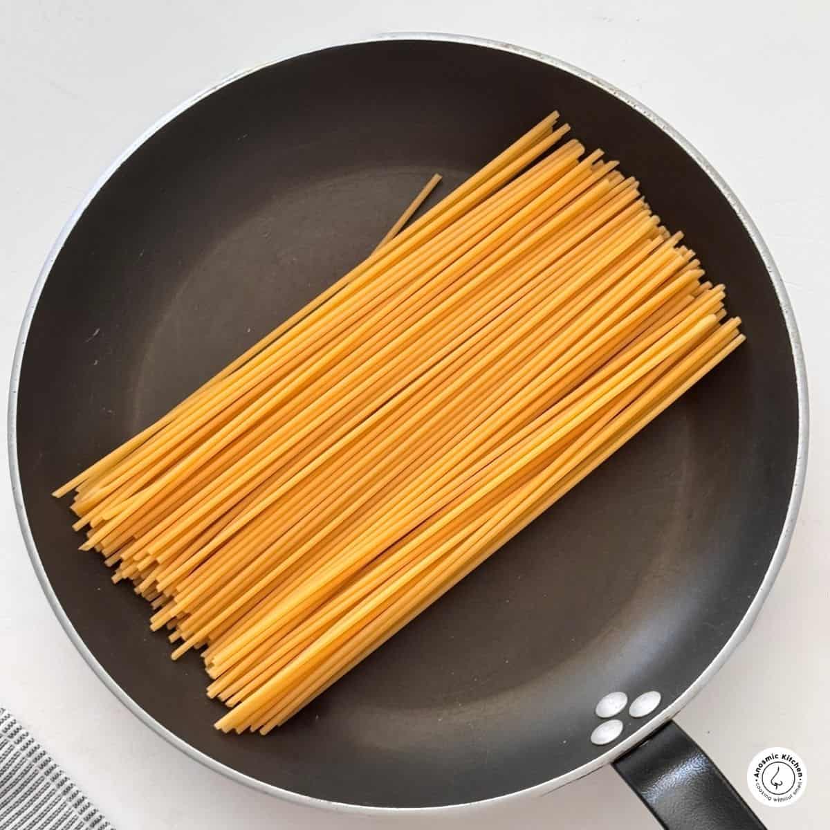 dry spaghetti in a dry skillet on a white background