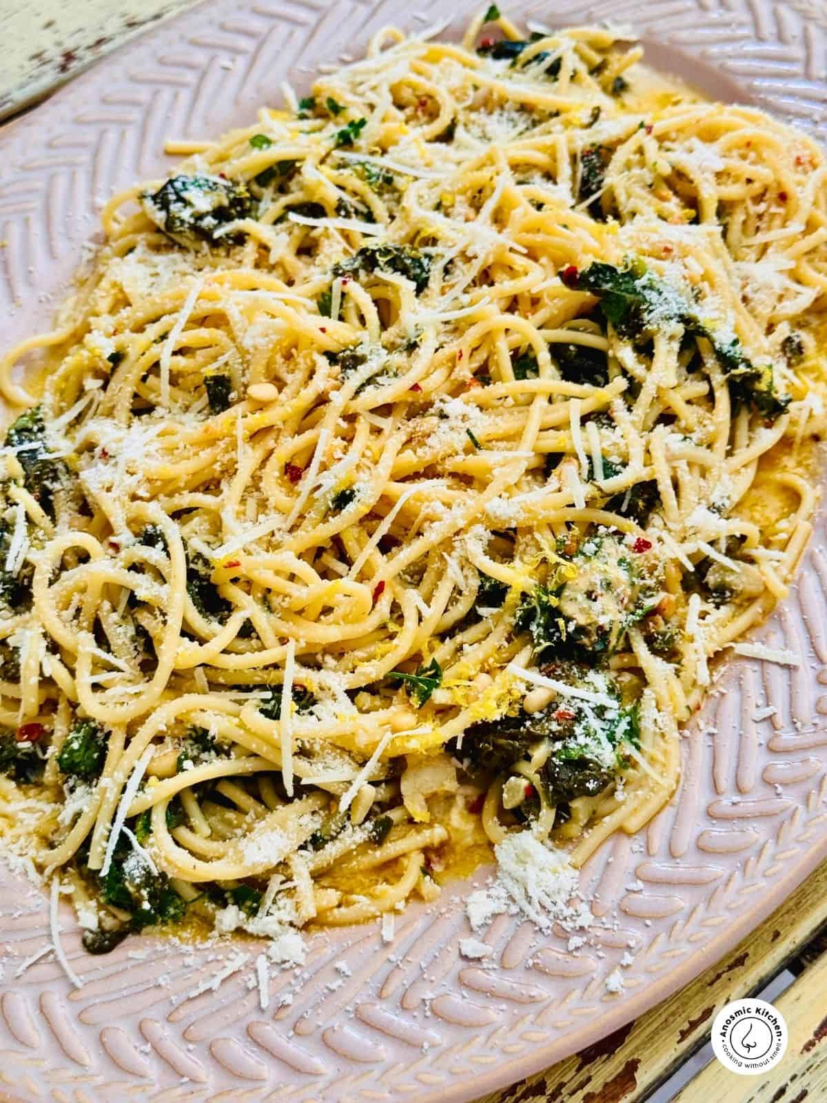 spaghetti lemon pasta with spinach and parmesan cheese on a platter.