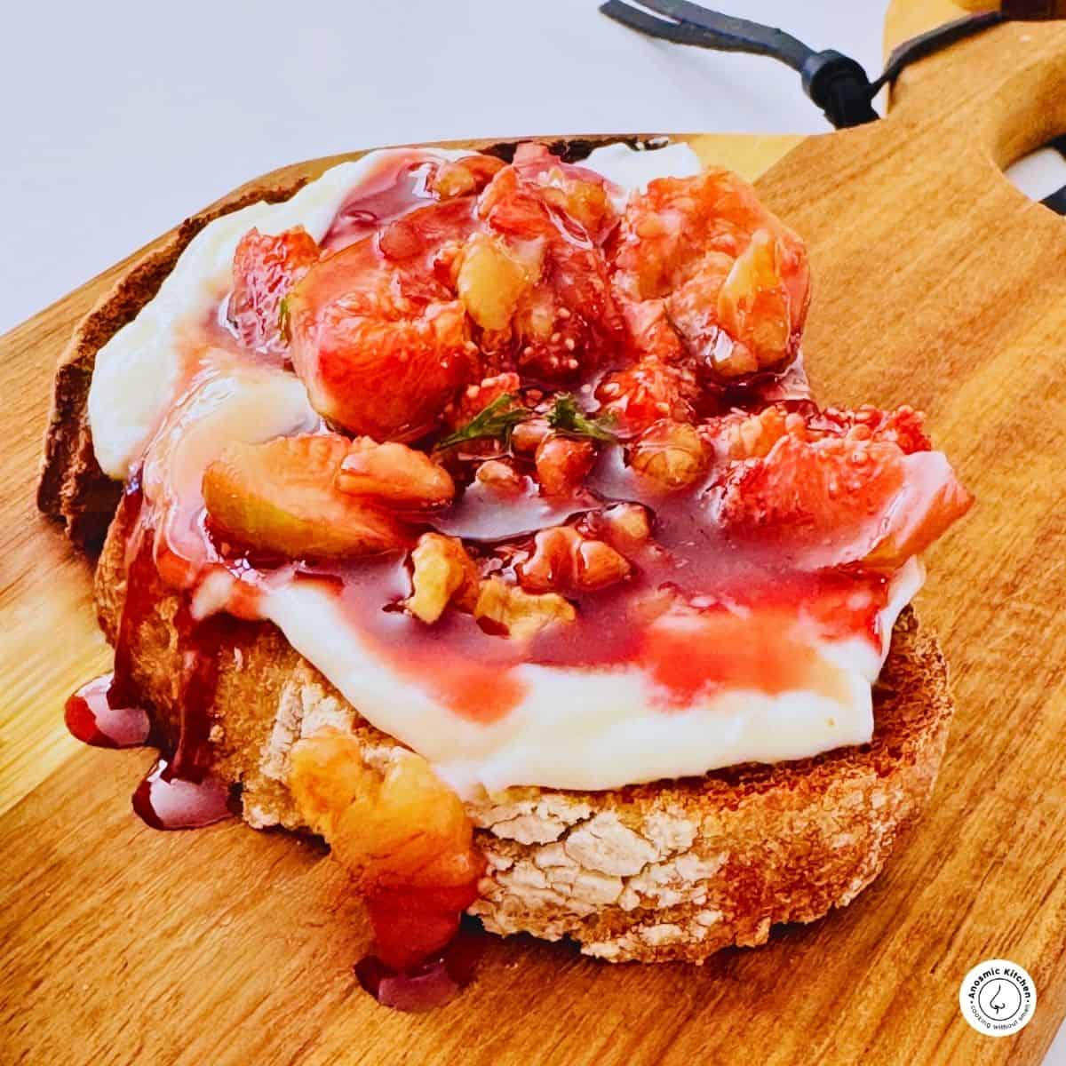 one bread slice on a board with mascarpone cheese and cooked fresh figs