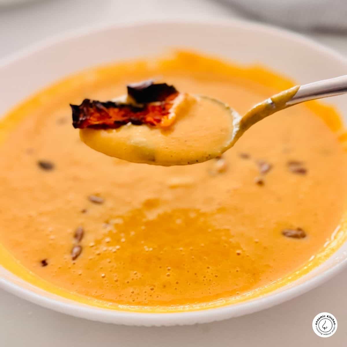 air fryer butternut soup with a piece of roasted butternut skin in a spoon