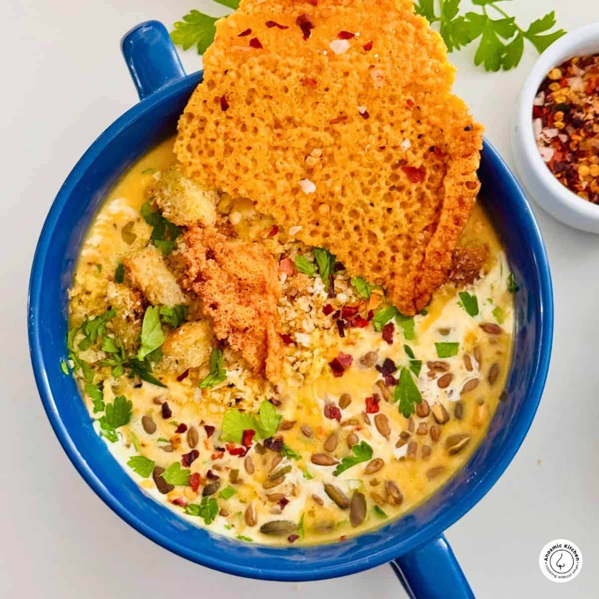 Cozy air fryer butternut squash soup with cheese crouton, parsley, and seeds, served in a rustic bowl