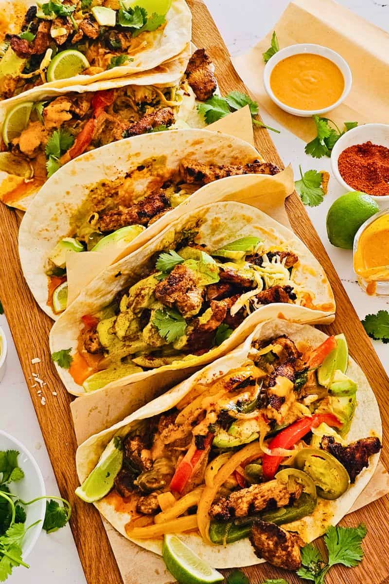 Grilled chicken strips in wraps with peppers, onions, and avocado