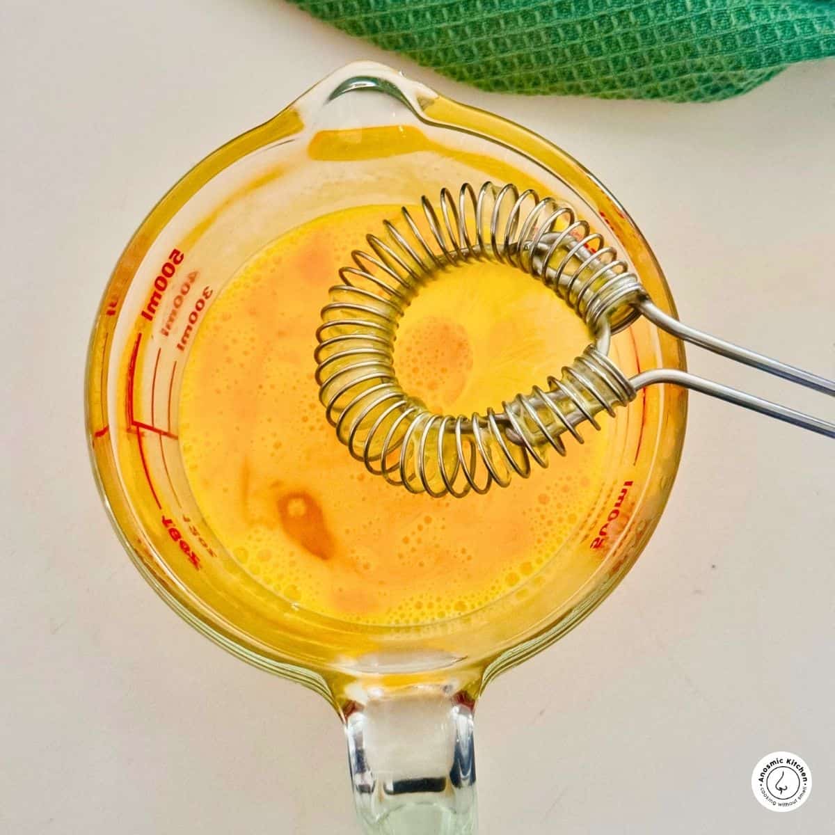 whisked eggs in a measuring jug with a whisk