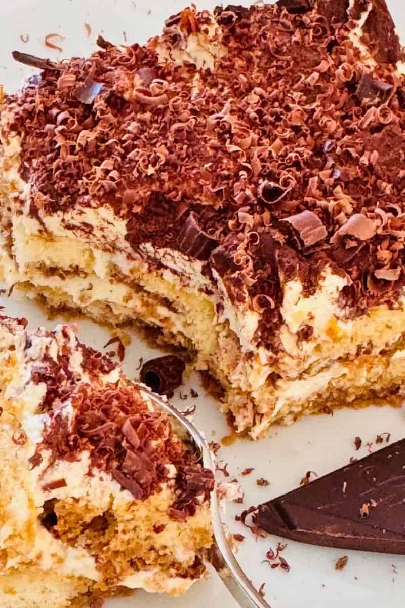 A slice of classic tiramisu with defined creamy layers, dusted generously with cocoa powder and served on a dessert plate.