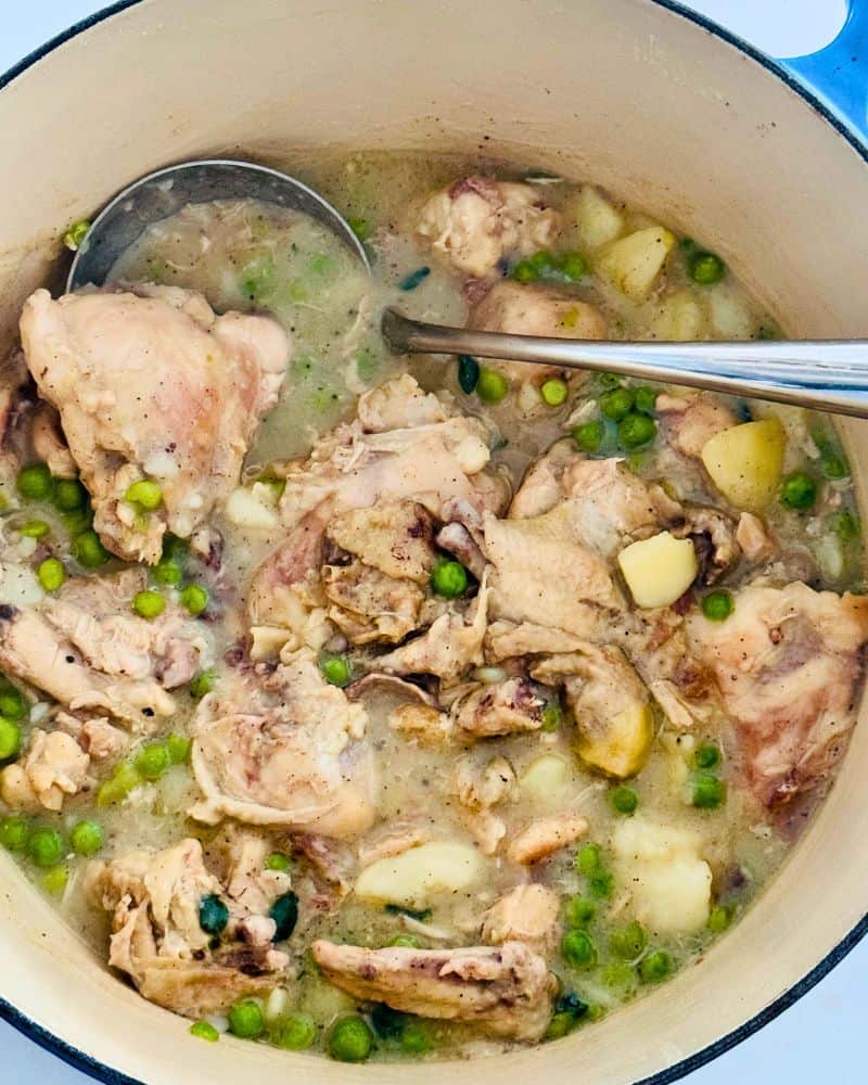 Easy chicken stew recipe served in a Dutch oven with tender chicken pieces, potatoes, and peas in a golden broth.