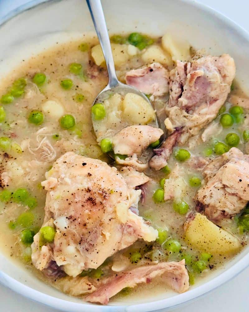 farm style chicken stew pieces cooked with potatoes and peas in a chicken broth