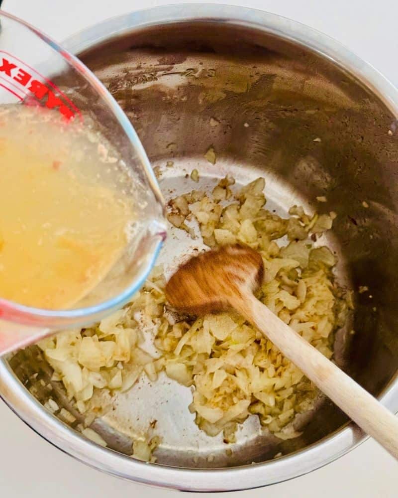 chopped onions in an inner pot fried, and broth pouring into the fried onions
