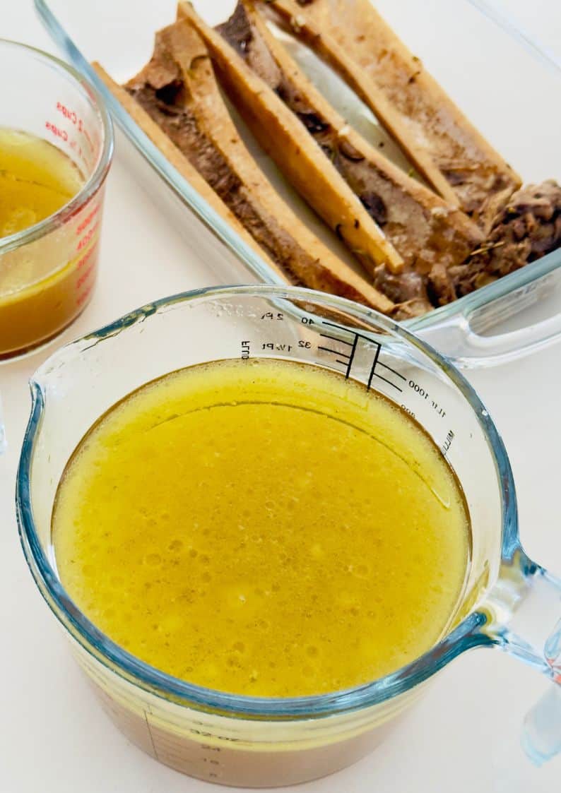 bone broth in jugs with cooked bones next to it.
