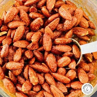 Air fryer sweet and spicy almonds being scooped with a spoon from a serving bowl.