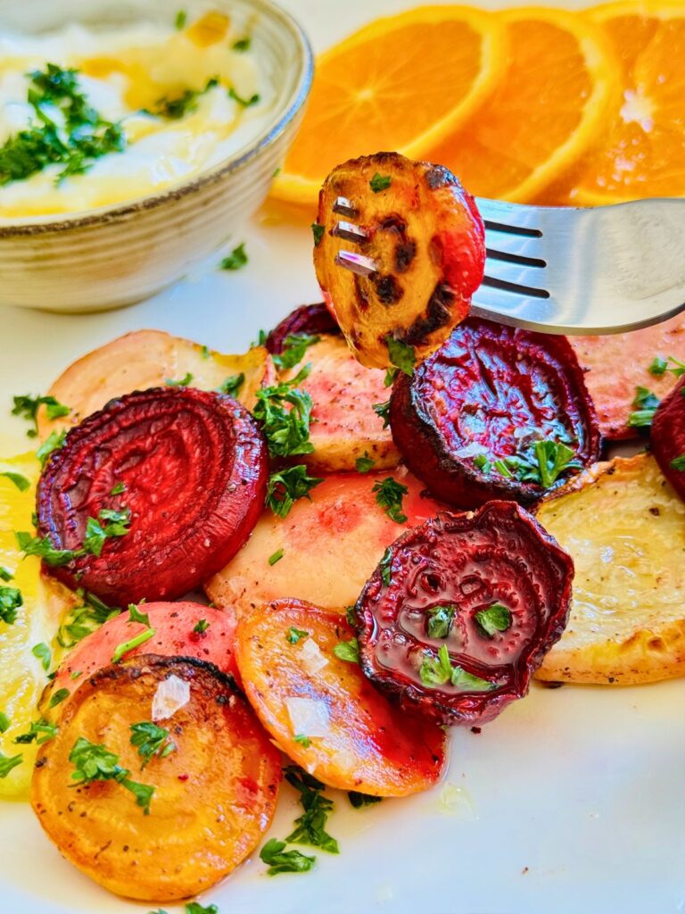 colorful roasted and sliced beetroot on a plate with a serving dip.