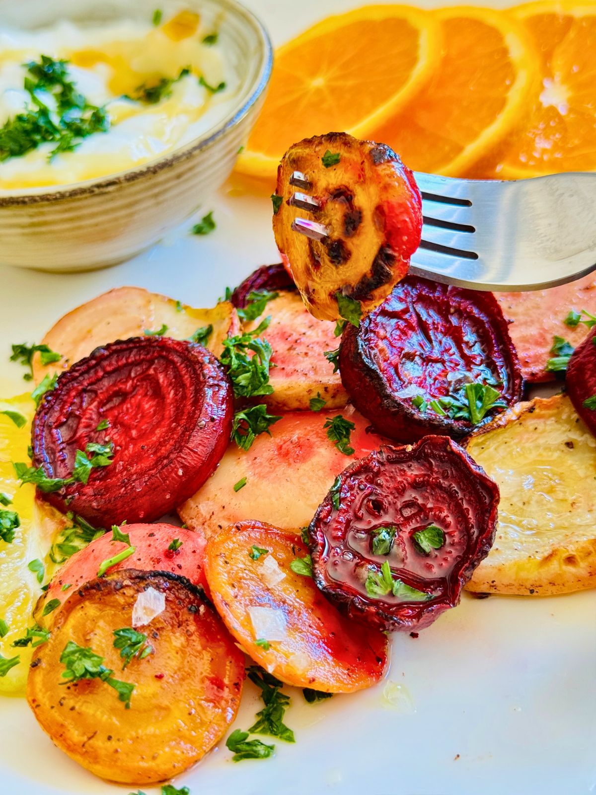 colorful roasted and sliced beetroot on a plate with a serving dip.