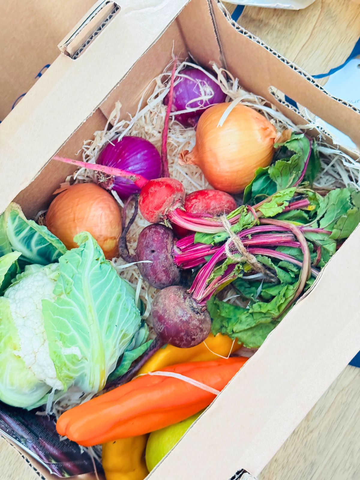 a box of fresh produce beetroot, onions, carrots, peppers, cauliflower