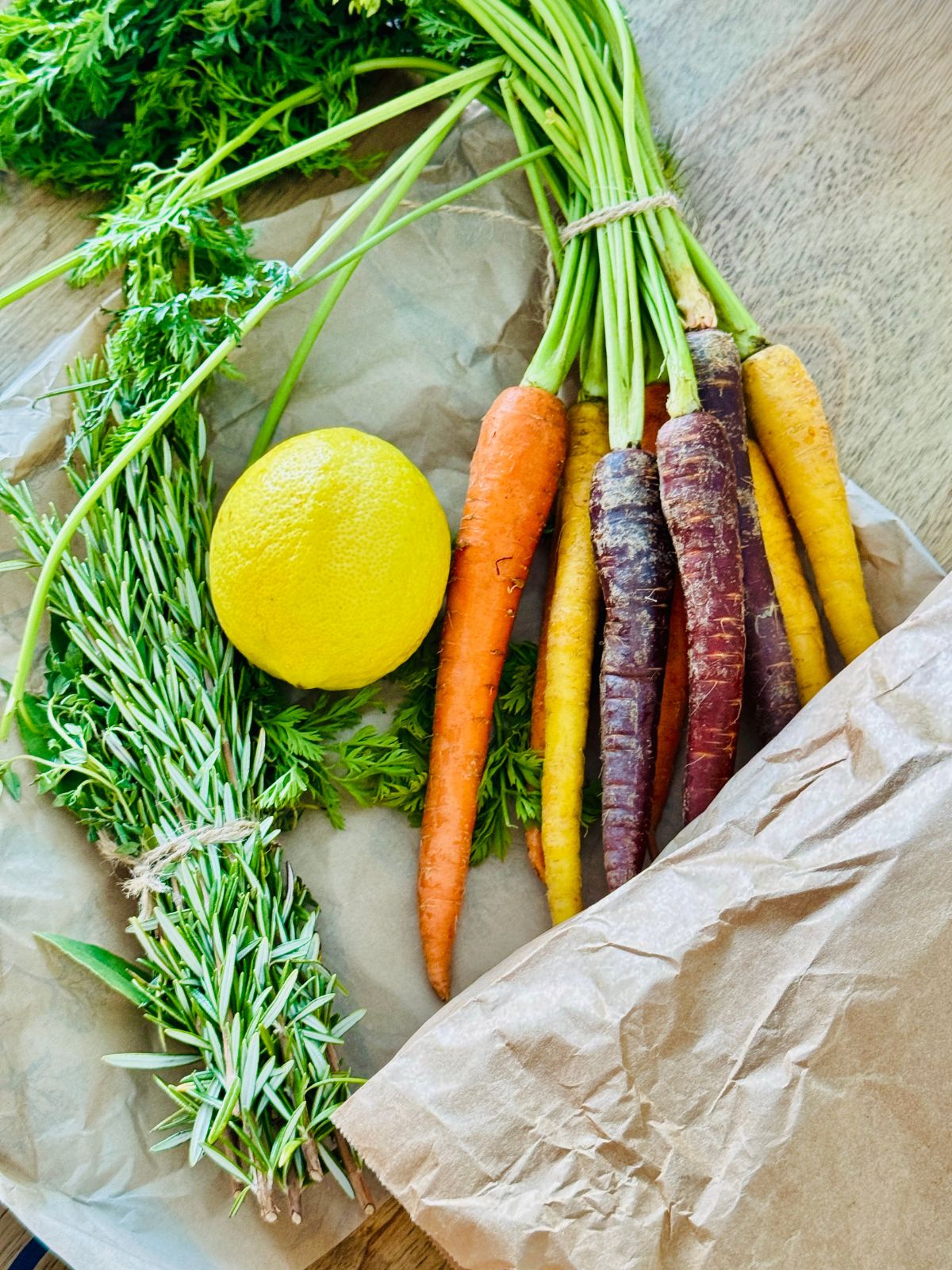 lemon, herbs and carrots on brown sheet of paper
