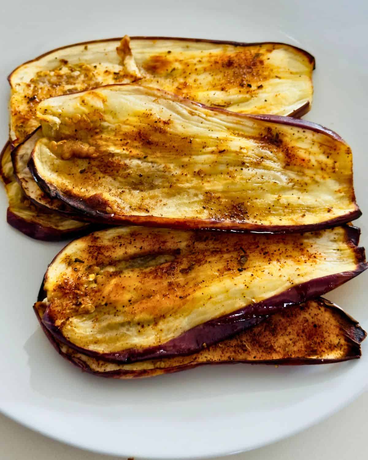Golden brown grilled eggplant (aubergine) slices on a plate, lightly charred
