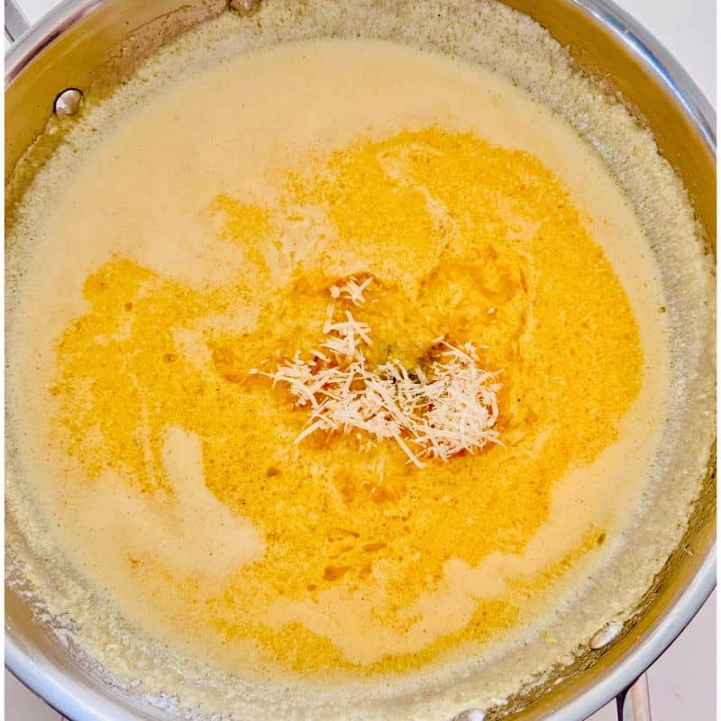 lemon, butter and cream in a pan with parmesan cheese being cooked.