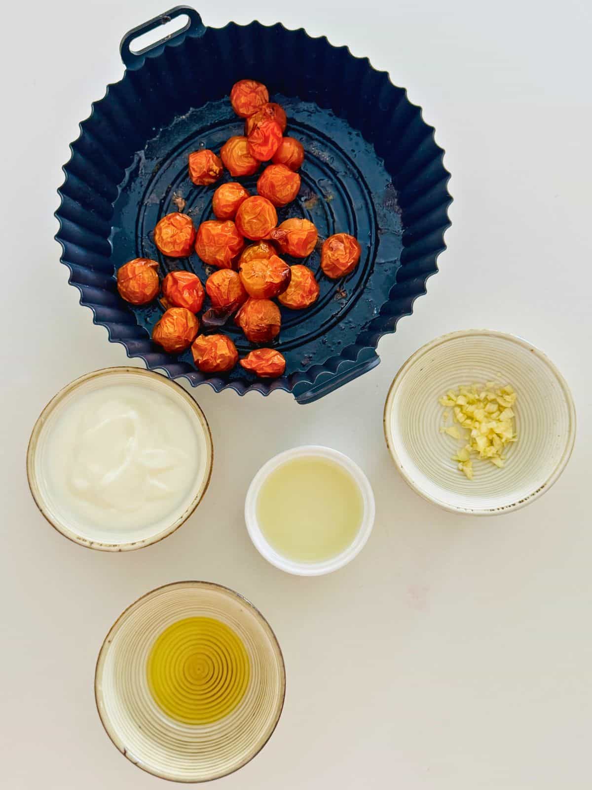 ngredients for pink sauce including roasted cherry tomatoes in an air fryer basket