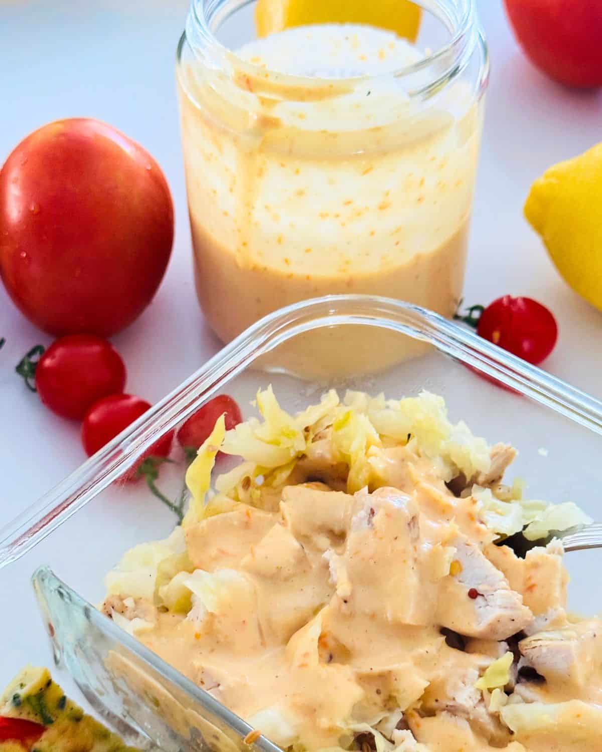 Pink sauce poured over a meal prep bowl with extra sauce in a jar behind