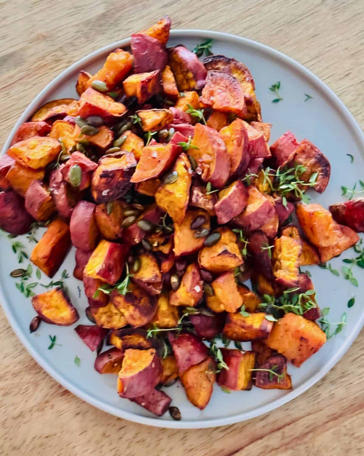 skin-on sweet potato cubes on a plate garnished with pumpkin seeds