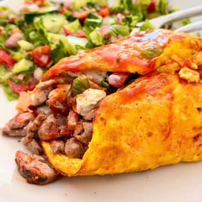 omelette stuffed with meat, served with a salad on the side
