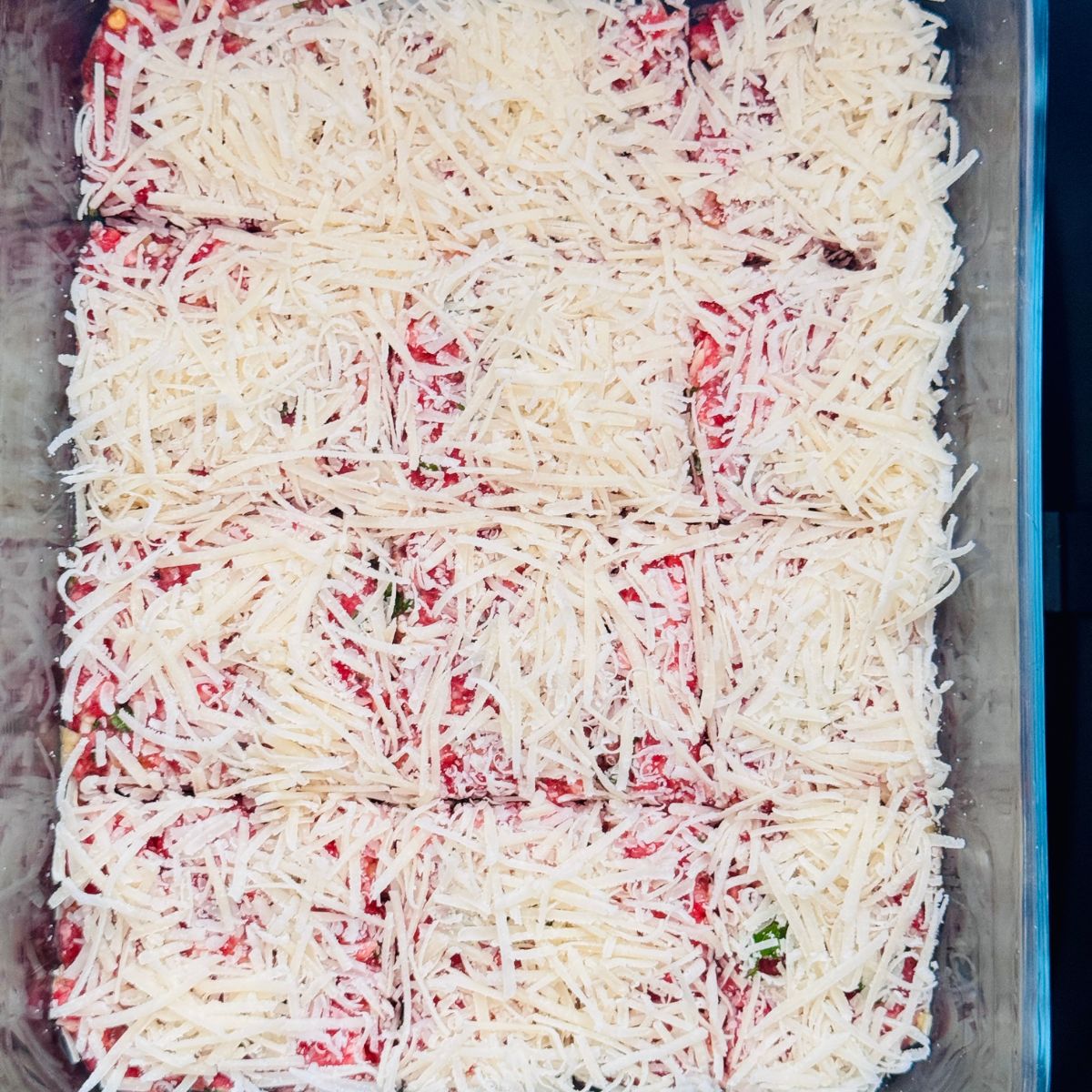grated parmesan cheese topped over ground beef in an air a dish ready to be air fried.