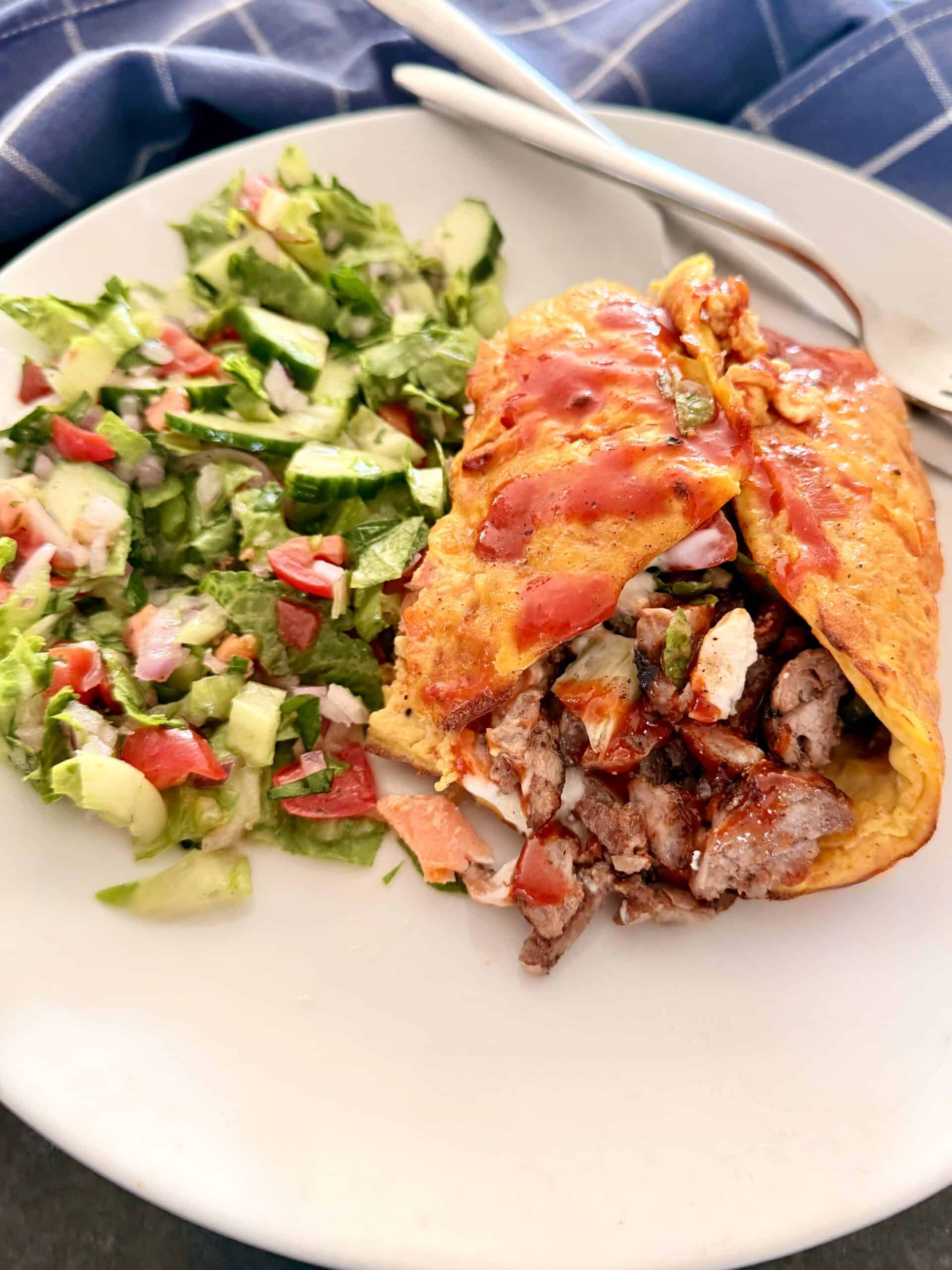 egg and cottage cheese omelette stuffed with beef, folded and served with a side salad.