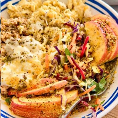 High-protein lunch bowl with scrambled eggs, ground chicken, rainbow slaw, sliced apple, yogurt and hemp seeds