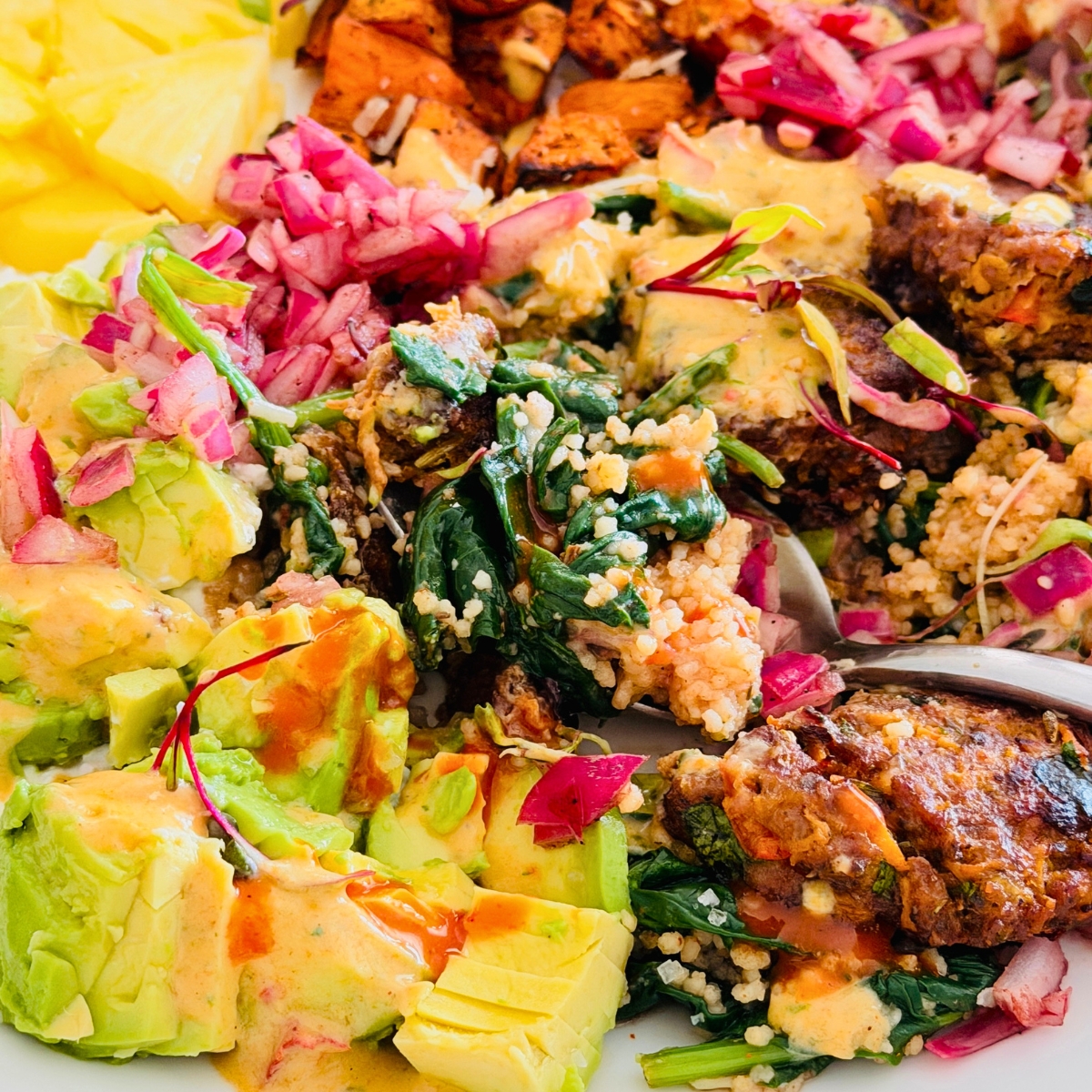 couscous and spinach on a plate with beef bites, red onion pickle and sweet potato