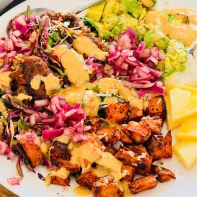 beef bites with avocado, sweet potato bowl served with avocado and a pink dressing.
